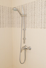 Shower hanging on the wall with beige tiles