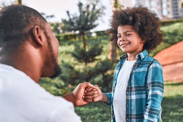 Cheerful child smiling and fist-bumping his father