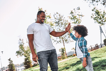 Joyous dad giving his son a high-five outdoors