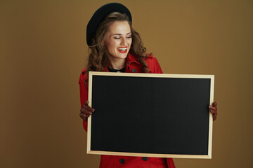 happy stylish woman showing blank board on brown background