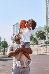 Happy dad holding kid on his shoulder during basketball