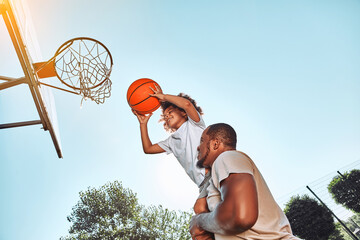 Joyful child playing basketball with his caring father