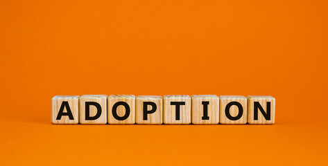 Wooden cubes with the inscription 'adoption'. Beautiful orange background, copy space.