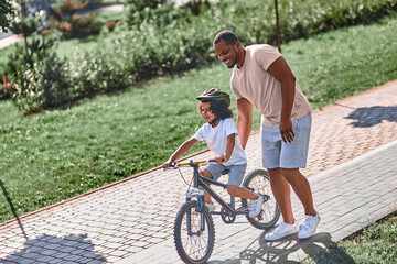 Responsible father helping his child with riding bicycle
