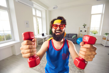 Happy athlete who decided to start fitness training with dumbbells is looking at camera and laughing