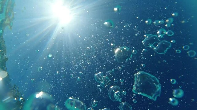 Underwater slow motion bubbles moving to surface in turquoise crystal clear pool