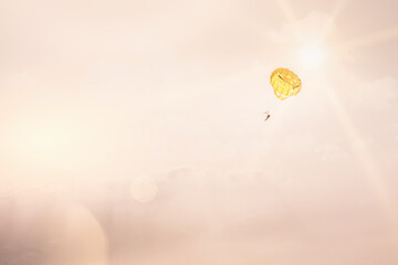 Paraglider in a pastel evening with the sun behind flying high in the sky