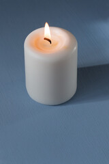 burning candle against light blue background 