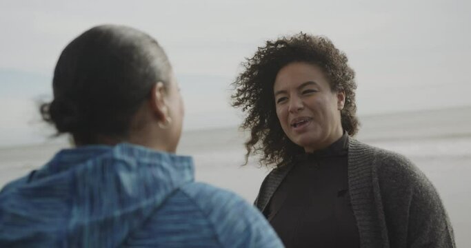 Two plus size females outdoors on beach talking, Obese black mother and daughter body positive fun