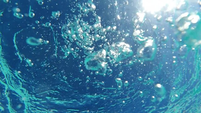Underwater slow motion bubbles moving to surface in turquoise crystal clear pool