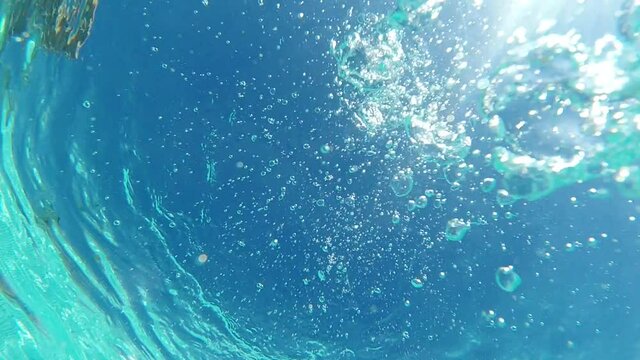 Underwater slow motion bubbles moving to surface in turquoise crystal clear pool