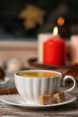 Hot tea and pastries with pecan on the sill window, rainy weather outside. Autumn seasonal decor composition with candles light. Cozy home concept.