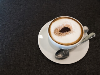 hot coffee in white and stanless spoon on black fabric background.copy space.