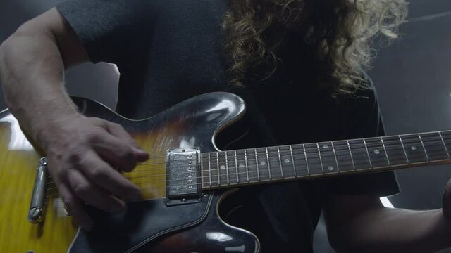 Professional musician with long hair playing guitar in recording studio (Cinematic Slow Motion)