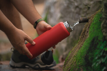 Detail of hands filling up an aluminum bottle from a natural source