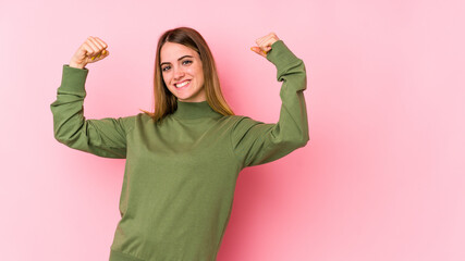 Young caucasian woman isolated on pink background showing strength gesture with arms, symbol of feminine power