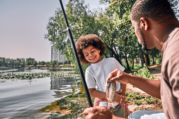 Afro-American dad and his son having successful fishing day