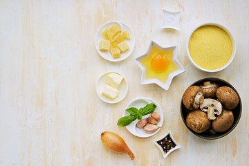 Prepared ingredients for cooking polenta with fried mushrooms and an egg on a light concrete background. Step by step recipes. Polenta and corn grits recipes.
