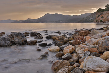 Rocky stretch of coast of the Mediterranean Sea on the Greek Aegean island of Samos with a calm water surface.