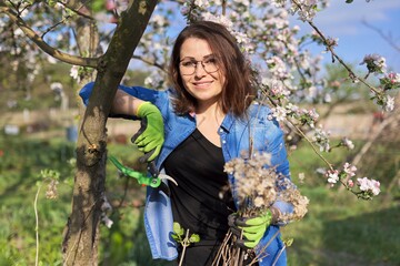 Woman gardener with dry branches of hydrangea smiling looking at camera