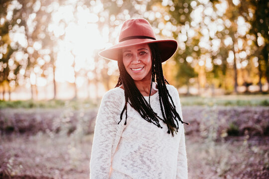 Portrait Of Mid Adult Hispanic Woman Wearing A Hat At Sunset During Golden Hour, Autumn Season