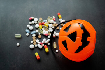 Close up plastic Pumpkin basket with colorful blurred pills poured out from it. Coronavirus...