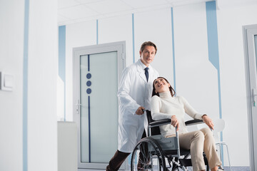 Selective focus of excited patient in wheelchair looking at doctor in clinic