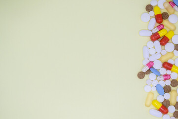 Obraz premium A lot of colorful tablets and pills on the right. Yellow background, copy space