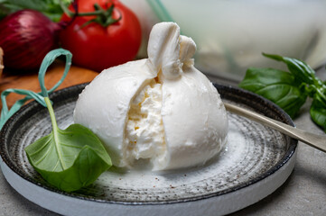Eating of fresh handmade soft Italian cheese from Puglia, white balls of burrata or burratina cheese made from mozzarella and cream filling