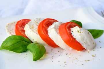 Caprese salad made with fresh soft white italian cheese mozzarella buffalo, green basil, red...