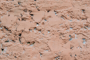 Old rough plaster, painted in pale pink or salmon color. Uneven background
