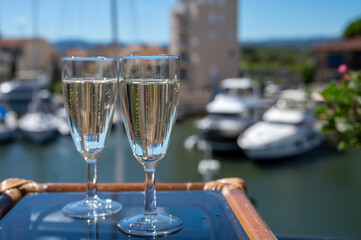 Summer party with sparkling champagne wine and sail boats haven of Port Grimaud on background, Provence, France