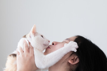 Close-up shot of an Asian woman holding a cat and kissing. This picture has space for putting description.