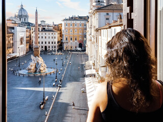 A woman looks out the window of a building above the Piazza Navona in Rome Italy