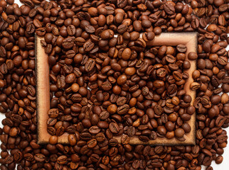 Wooden brown frame on coffee beans background. Concept of coffee drink time.