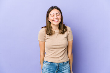 Young caucasian woman laughs and closes eyes, feels relaxed and happy.