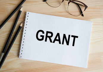 Write in a GRANT notebook, next to pencils and glasses.