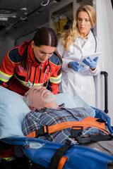 Selective focus of senior patient lying on stretcher near paramedic and doctor with digital tablet in ambulance auto © LIGHTFIELD STUDIOS