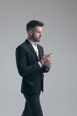 Confident elegant man adjusting his rings, wearing suit