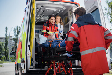 Selective focus of doctor with digital tablet standing in ambulance car near paramedics with...