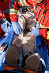 Fototapeta na wymiar Selective focus of paramedic locking belts of stretcher near patient and colleague in latex gloves