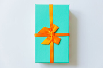 Christmas New Year birthday valentine celebration present romantic concept. Simply minimal design blue gift box with orange ribbon isolated on white background. Flat lay top view copy space.