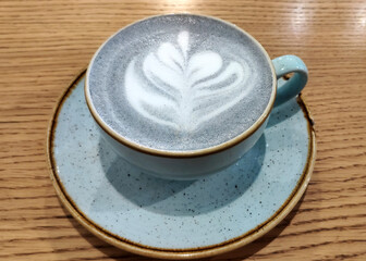 Cup of blue Cappuccino coffee on wooden table, hot drink close up