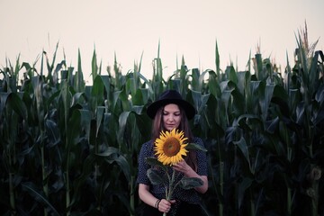 Beautiful young woman in a field of sunflowers in a hat. 
