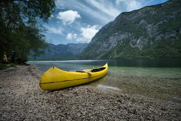 Beach lake shore with a yellow canoe, backgeound alps