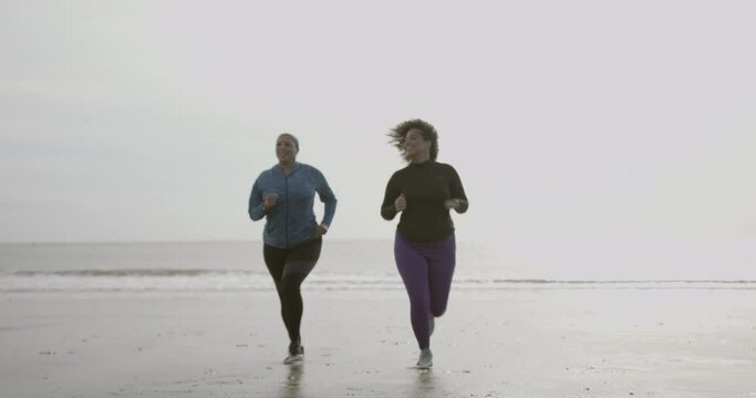 Mother and daughter running exercising outdoors on beach, Obese black women sports training body positive