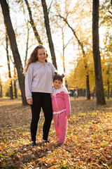 Two sisters standing in autumn park hugging