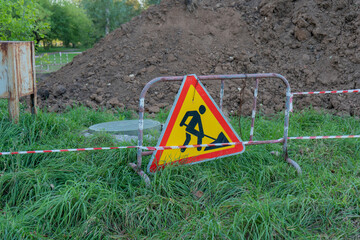 road works sign on the background of a pile of earth