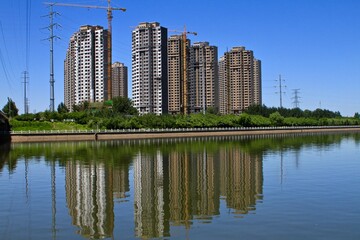 Fototapeta premium Modern apartment building under construction with a pond in the front