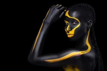 Gesichtskunst. Frau mit schwarzer und gelber Körperbemalung. Junges afrikanisches Mädchen mit bunter Körperfarbe. Ein erstaunliches Modell mit gelbem Make-up. Nahaufnahme Gesicht. © Mike Orlov